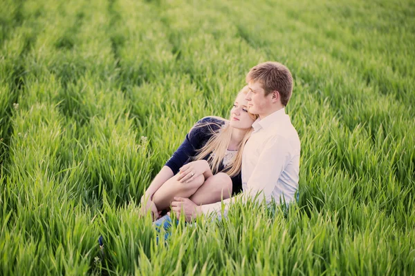 Jeune couple assis sur l'herbe verte — Photo