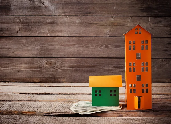 A paper houses stands over a wooden background. — Stock Photo, Image