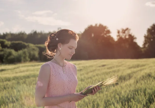 Jeune femme debout sur un champ de blé — Photo