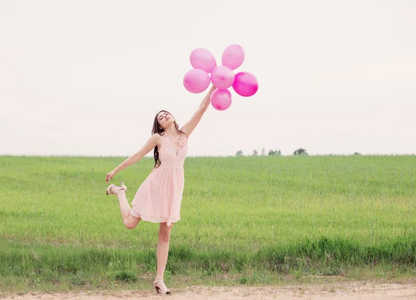 Flicka med ballonger i ett fält — Stockfoto