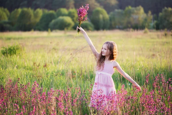 Belle fille avec des fleurs roses sur prairie — Photo