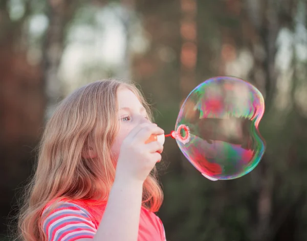 Chica soplando burbujas de jabón al aire libre — Foto de Stock