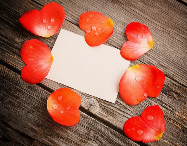Rode petal met papier op houten achtergrond — Stockfoto