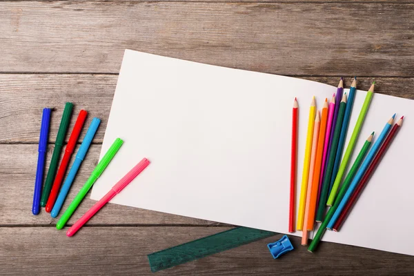 Χαρτί και πολύχρωμα μολύβια στο ξύλινο τραπέζι — Φωτογραφία Αρχείου