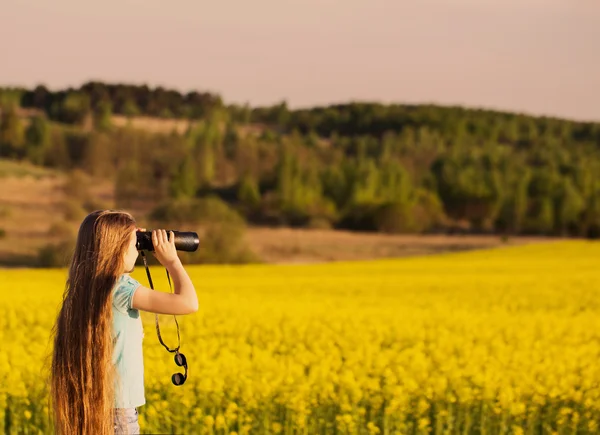 Meisje met een verrekijker in veld — Stockfoto