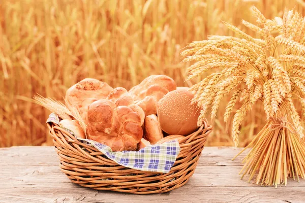 Pão e trigo na mesa de madeira no campo de outono — Fotografia de Stock