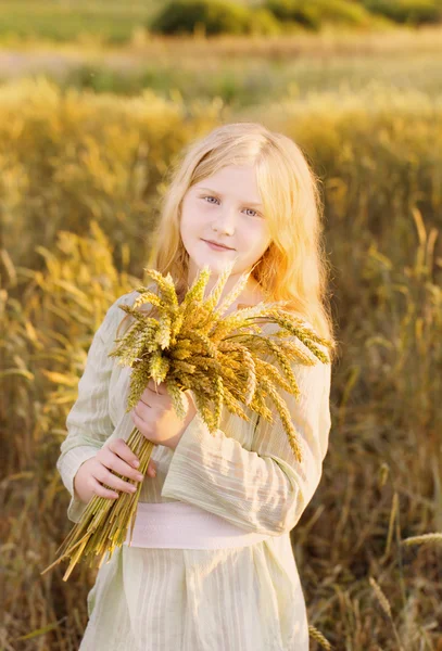 Happy child holding wheat ears at field — Stock Photo, Image