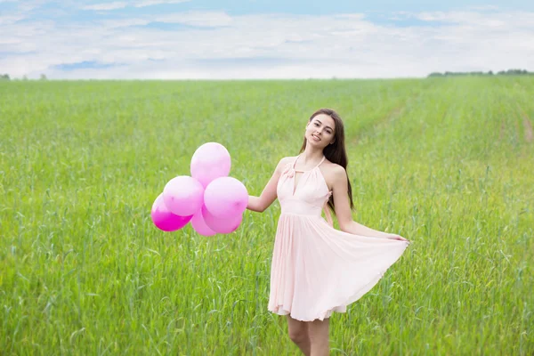 Jovem menina bonita com balões no campo — Fotografia de Stock