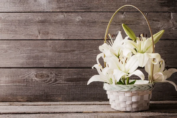 Weiße Lilie im Korb auf hölzernem Hintergrund — Stockfoto
