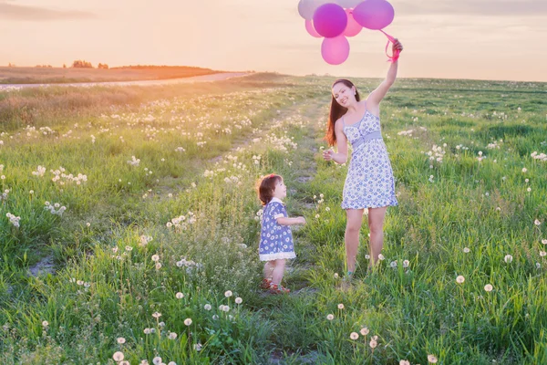 Bebê e mãe com balões ao ar livre — Fotografia de Stock