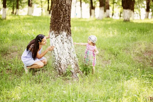 Mother and adorable baby daughter playing together hiding in sum — Stock Photo, Image