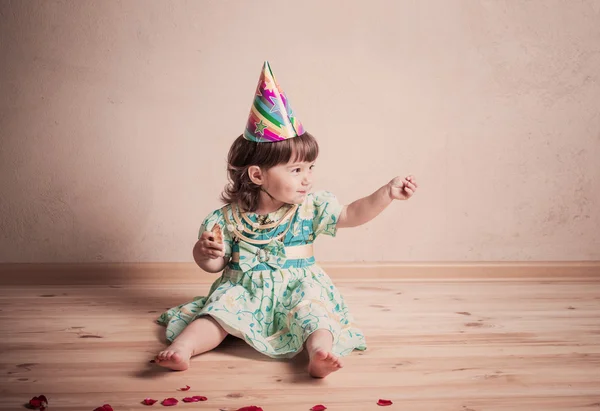 Маленька дівчинка їсть торт у святковій шапці в вінтажному стилі — стокове фото