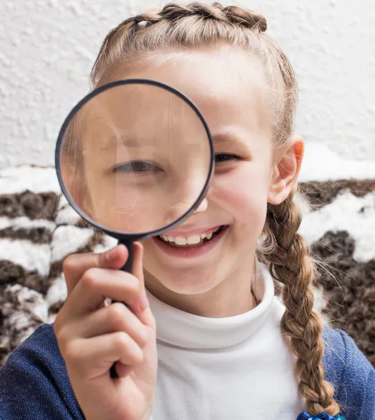 Girl looking through a magnifying glass — Stock Photo, Image