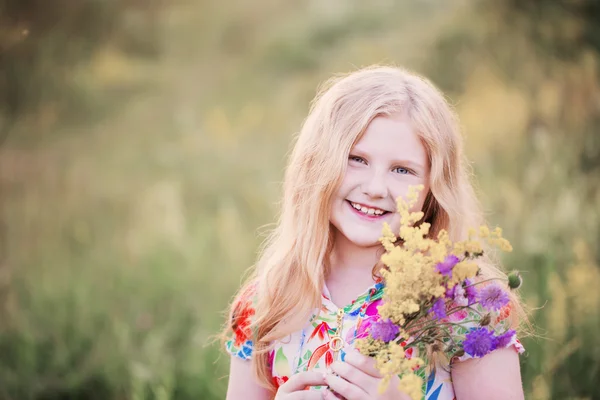 Glad tjej med flowersl på äng — Stockfoto