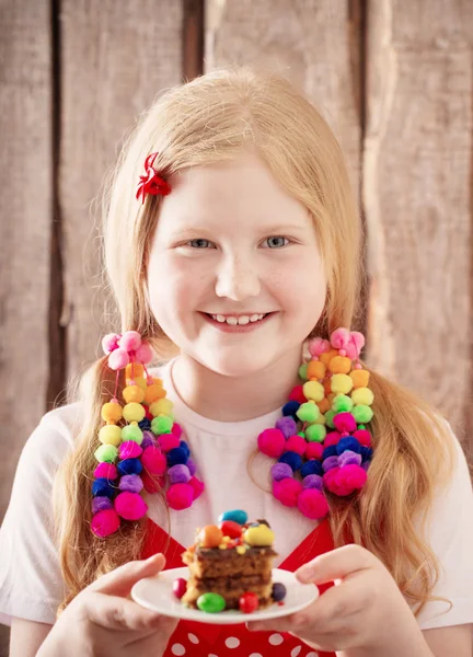 Sorriso menina com bolo no fundo de madeira — Fotografia de Stock