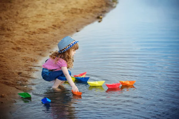Ребенок играет с бумажными лодками в воде — стоковое фото