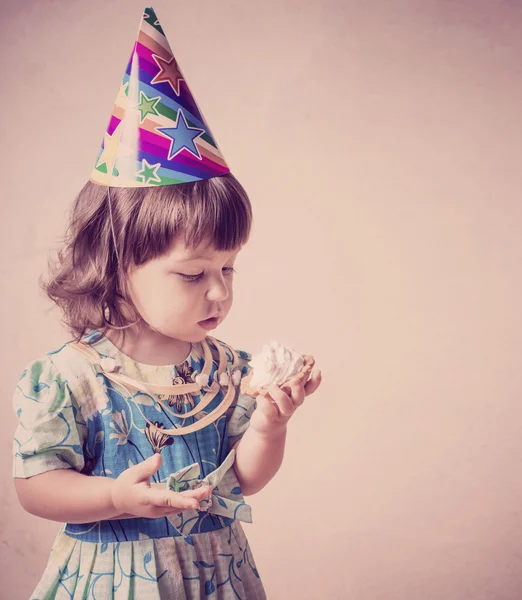 Little girl eating cake in a festive cap  in vintage style — Stock Photo, Image