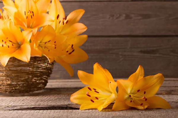Orange lily in basket on wooden background — Stock Photo, Image