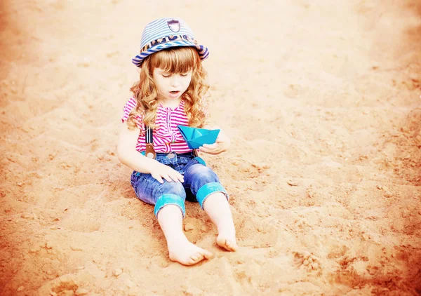Bambino che gioca con barche di carta sulla sabbia — Foto Stock