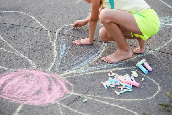 Das Kind, das eine Kreide auf den Asphalt zeichnet — Stockfoto