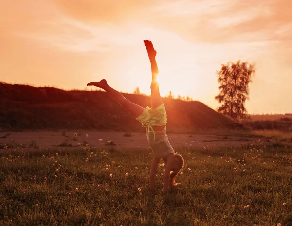 Fille faisant un handstand dans une prairie — Photo