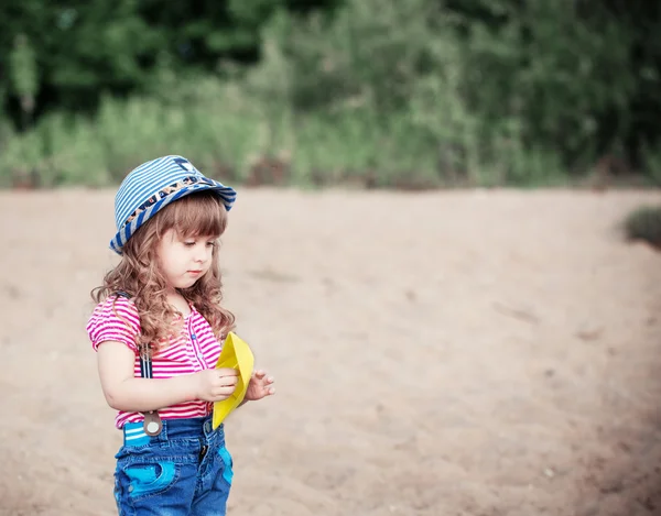 Child playing with paper boats on sand — Stock Photo, Image