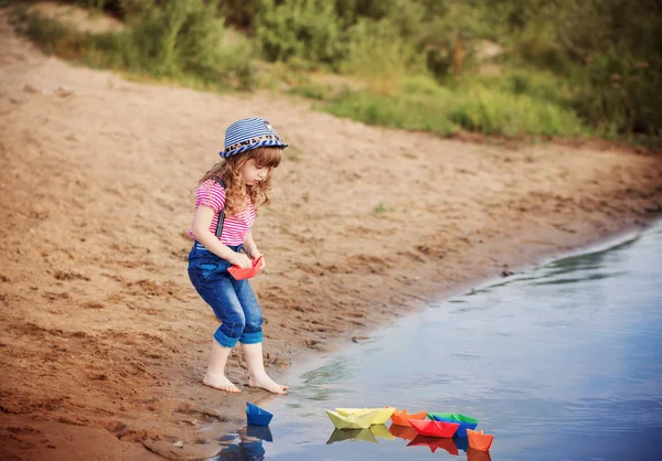 Sorridere bambino giocando con barche di carta in un fiume — Foto Stock