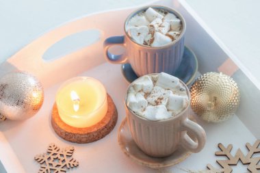 iki bardak sıcak içecek ve beyaz ahşap tepside noel süsü.