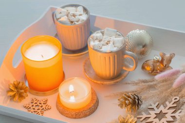 iki bardak sıcak içecek ve beyaz ahşap tepside noel süsü.