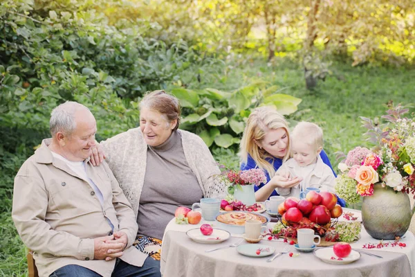 快乐的家庭在花园里摆满苹果派的餐桌旁 — 图库照片
