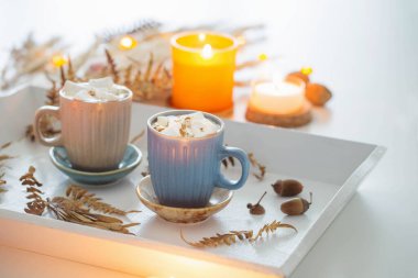 Marşmelovlu iki fincan kahve ve beyaz ahşap tepside sonbahar dekoru.