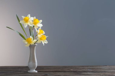 Sarı narsisli vazoda, ahşap masada, koyu arkaplanda.