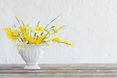 Vazoda beyaz ve sarı bahar çiçekleri arka planda eski beyaz duvarda