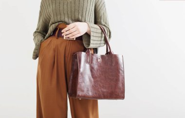 Beyaz arka planda çantalı modern elbiseli bir kız.