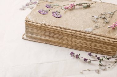 Kurumuş çiçekler ve eski kağıt üzerinde eski bir kitap.