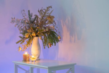 Akşamları arkaplan duvarında yanan mumlar olan Noel buketi.