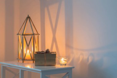 Çok renkli ışıklandırılmış duvarın arka planında yanan mumlar olan ahşap fener.