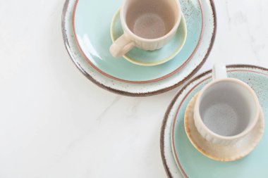 Beyaz mermer masada iki seramik bardak ve tabak.