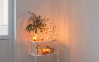 Akşamları beyaz arka planda yanan mumlarla Noel süsleri.