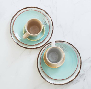 Beyaz mermer masada iki seramik bardak ve tabak.