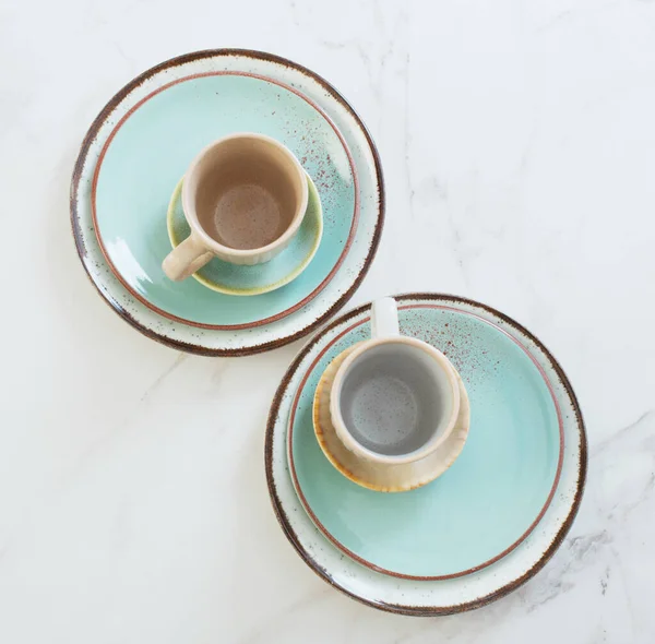 Beyaz mermer masada iki seramik bardak ve tabak.