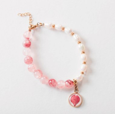 Beyaz zemin üzerinde doğal taşlardan yapılmış pembe ve beyaz bilezikler.