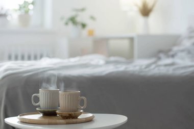 Yatak odasındaki tahta tepside iki fincan kahve.