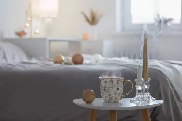 Beyaz Yatak Odasındaki Küçük Masada Noel Topları Olan Bir Fincan — Stok fotoğraf
