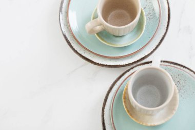 Beyaz mermer masada iki seramik bardak ve tabak.