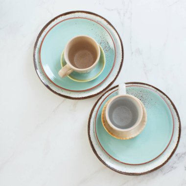 Beyaz mermer masada iki seramik bardak ve tabak.