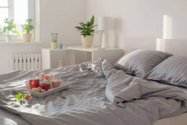 Yatakta iki kırmızı kahve ve çiçek.