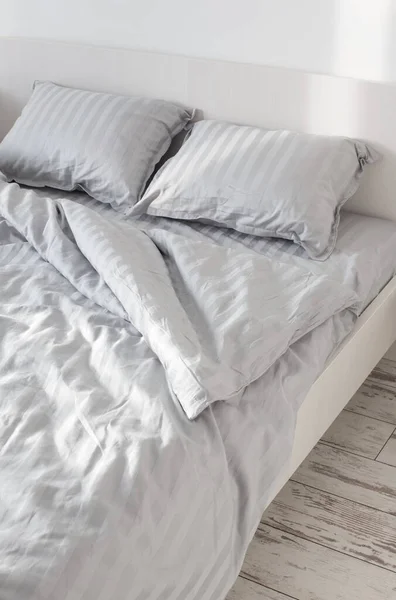 gray linens in sunlight on  bed in  bedroom