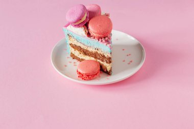 Pembe ve mavi desenli bir parça kek beyaz tabakta pembe arka planda