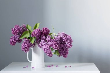 güzel leylak çiçekleri beyaz sürahi içinde ahşap masada